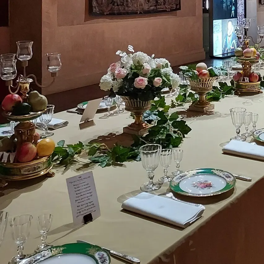 Photo d'une longue table de banquet, finement dressée, avec des belles décorations florales